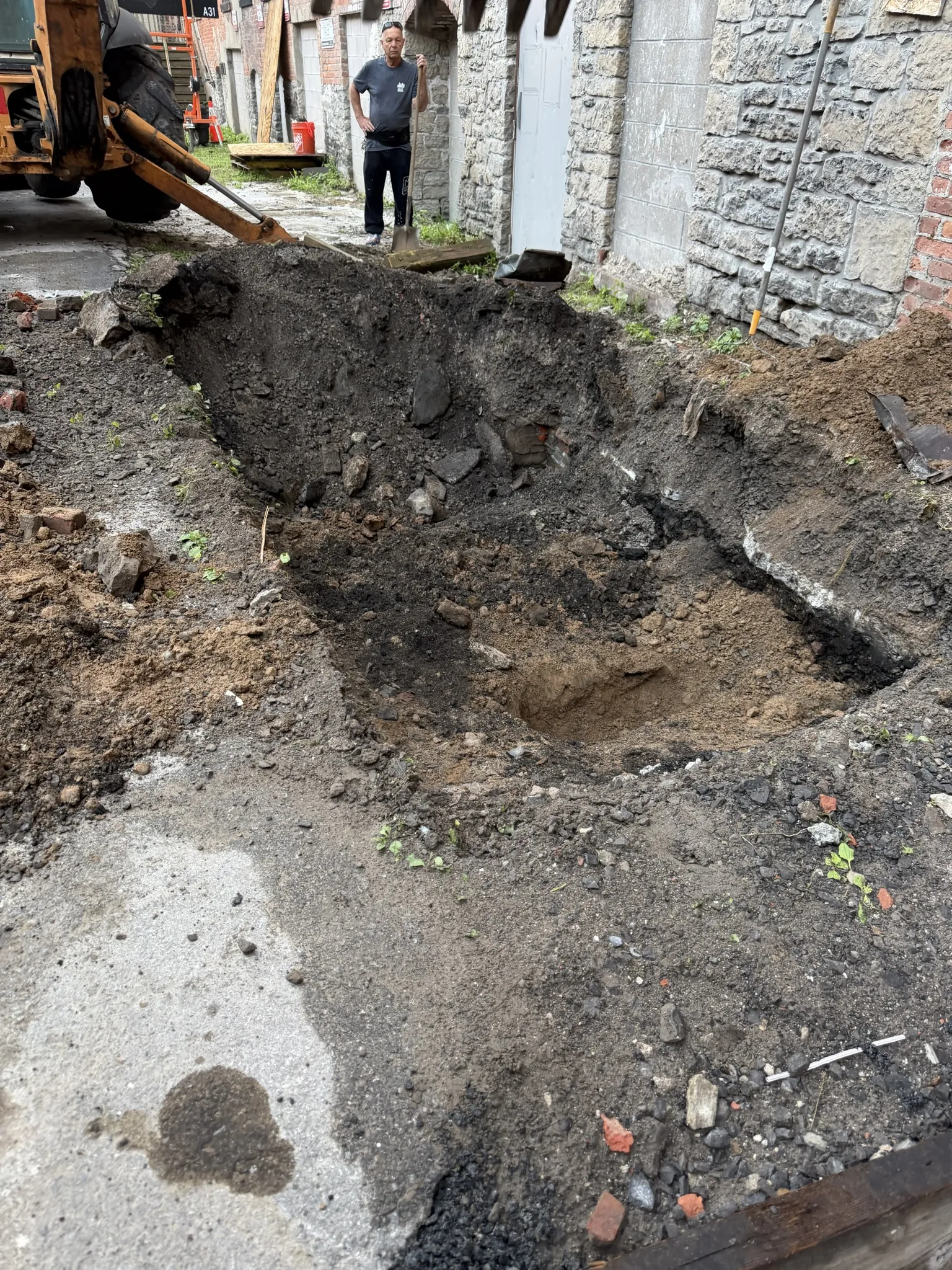 Excavated pit revealing old foundation debris and brick