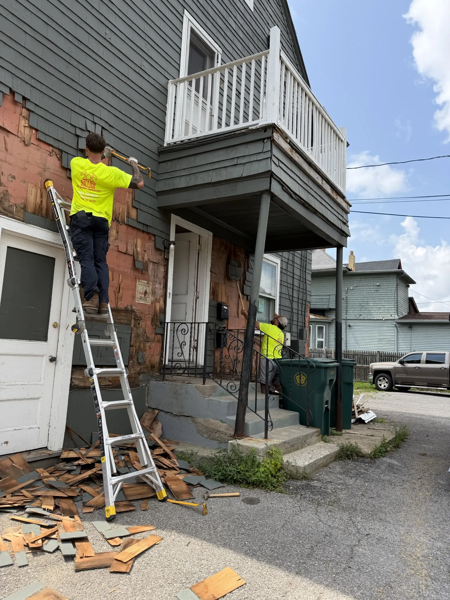 SOS General Contractors crew removing old siding from house exterior