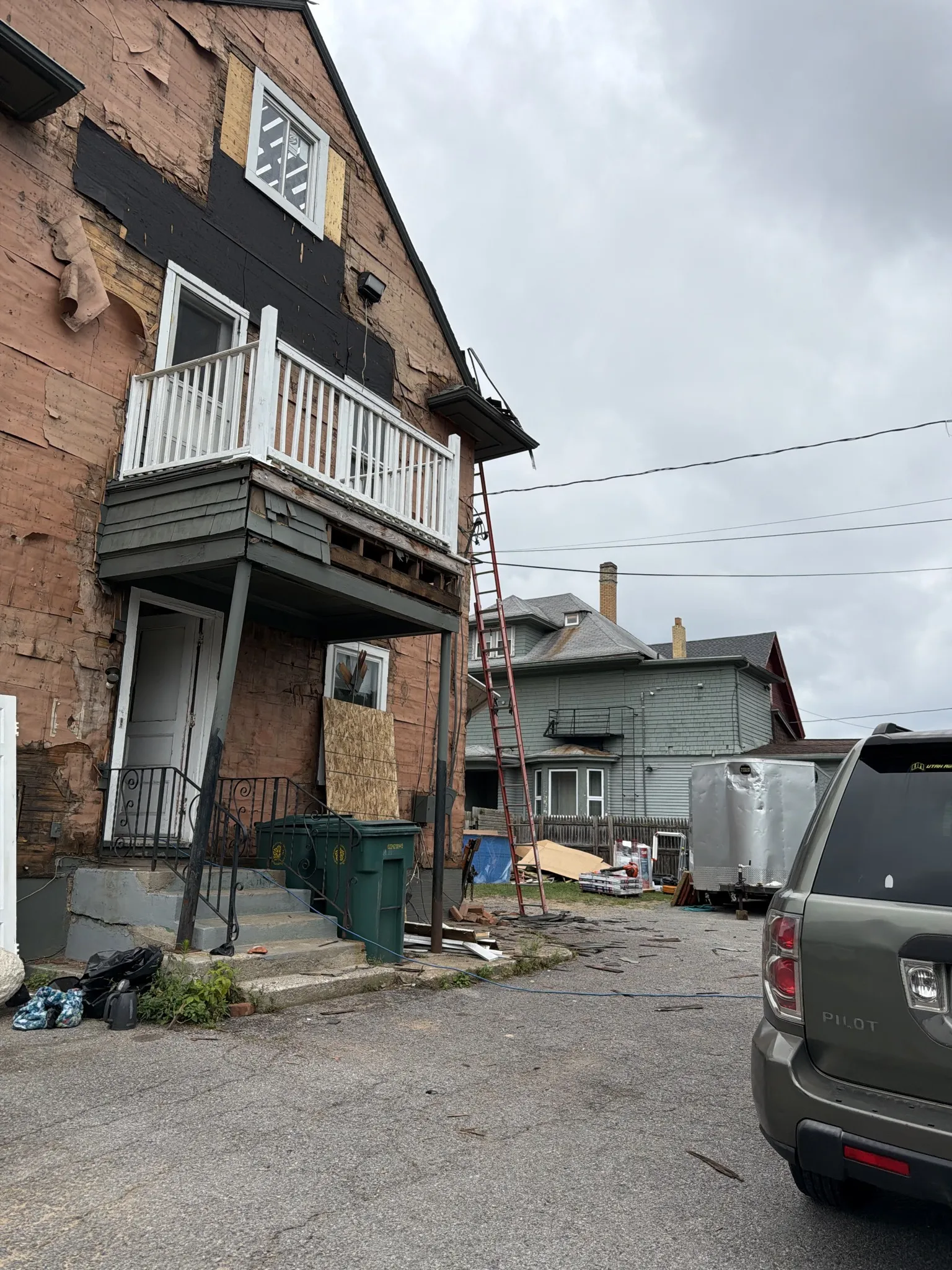 House exterior mid-renovation with siding removed and materials staged for reinstall
