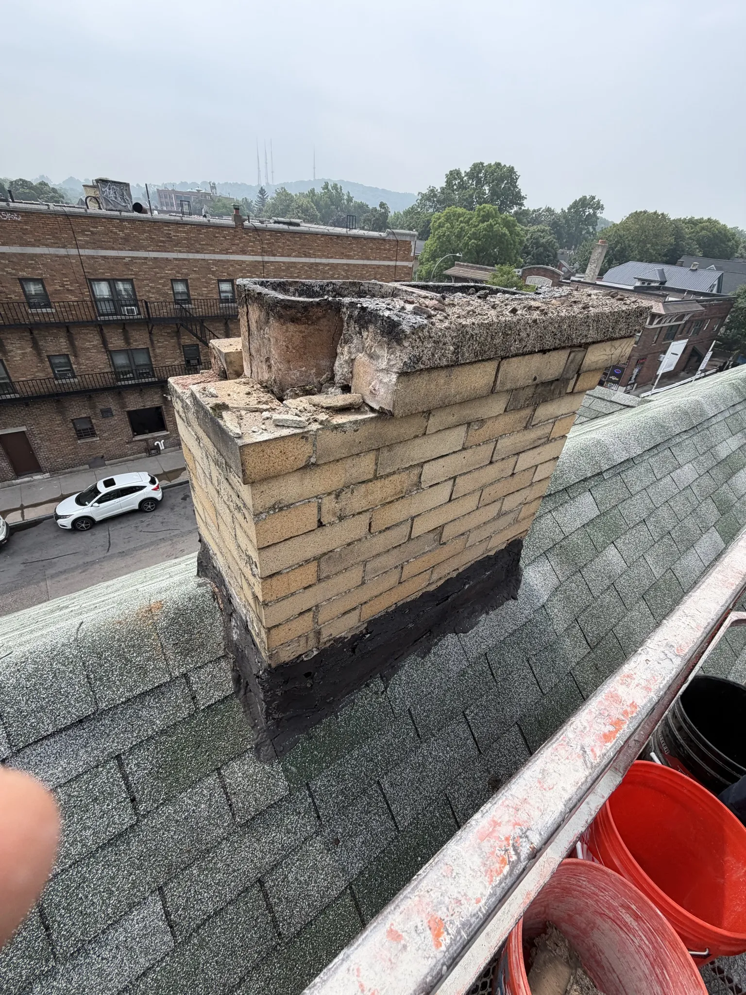 Partially demolished chimney on rooftop before removal