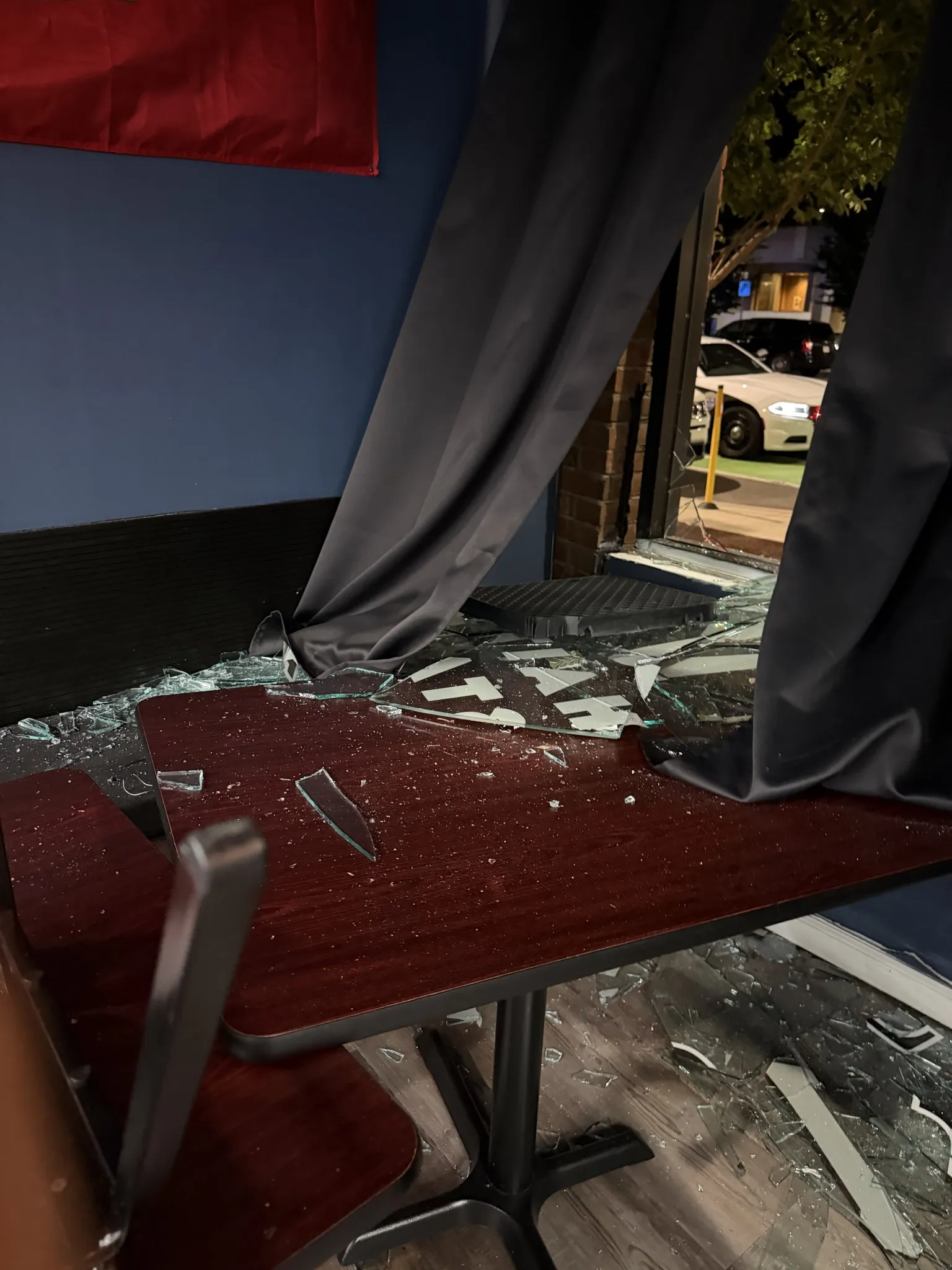 Shattered storefront window with debris on interior seating